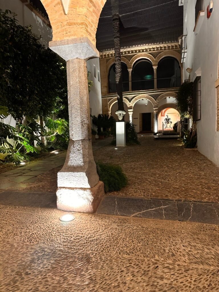 Lit stone column and arched courtyard at night