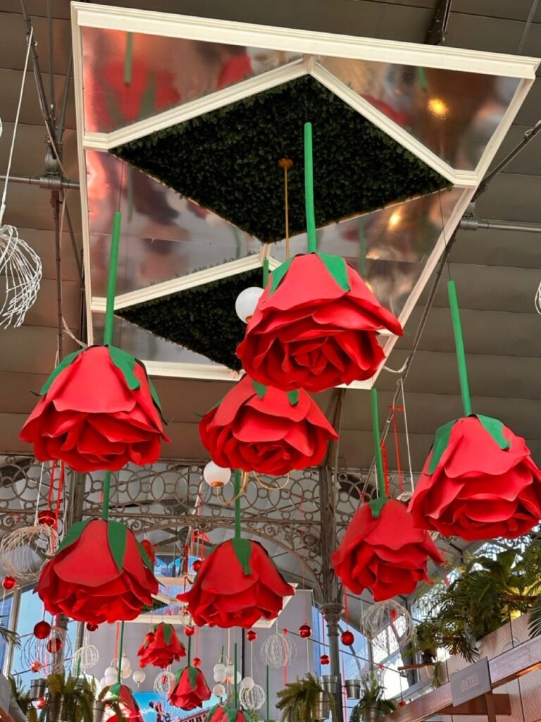 Red paper roses hanging from the ceiling of a covered food market