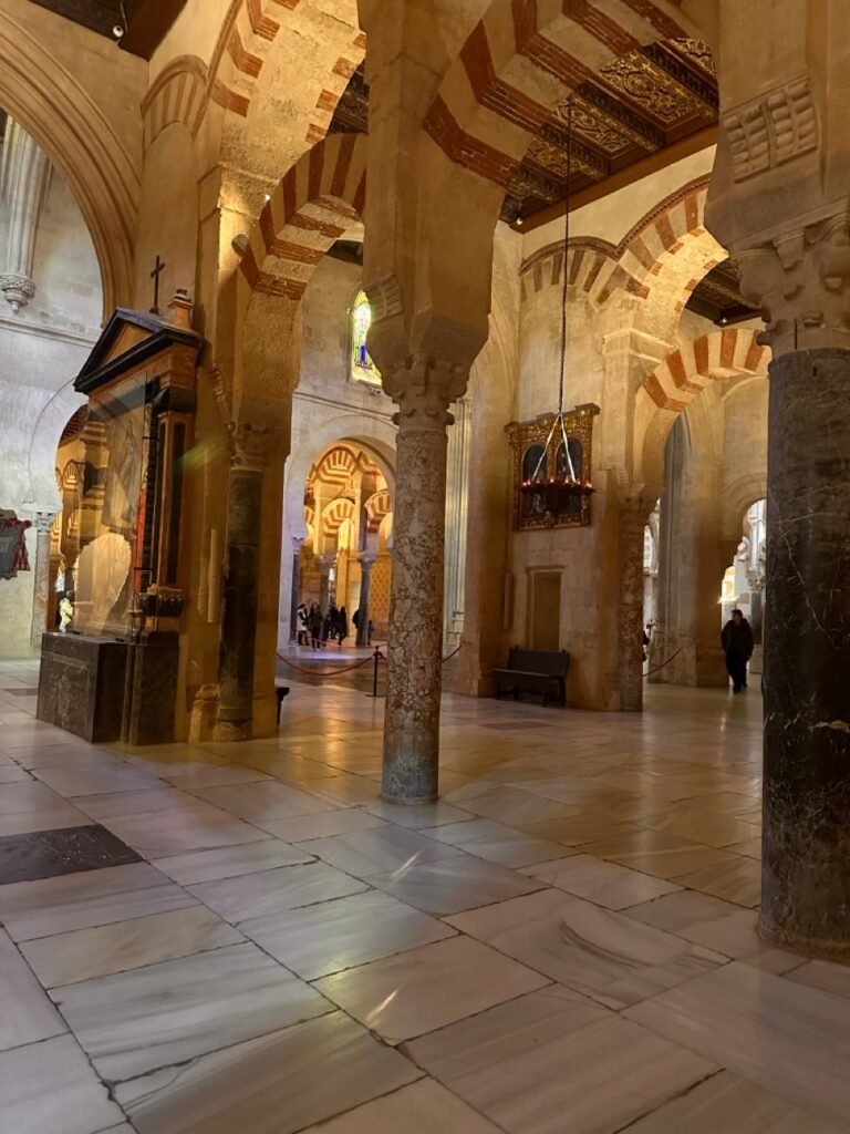 Stone columns and red-and-white arches above a marble floor in the Mezquita