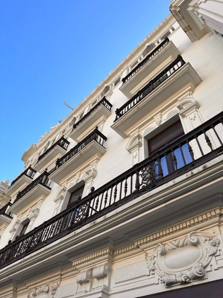 White building with wrought-iron balconies against a blue sky